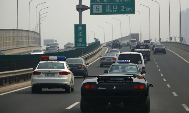 Wang Yu drives a handmade replica of Lamborghini Diablo next to a police car on a highway during a test drive in Beijing